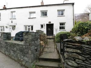 a white house with a stone wall and a gate at Nightingale Cottage in Threlkeld