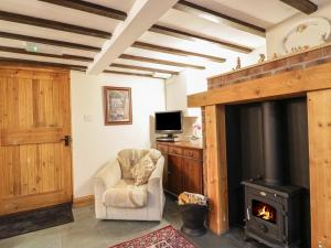 a living room with a fireplace and a chair at The Old Barn in Nether Wasdale