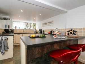 une cuisine avec un comptoir et deux chaises rouges dans l'établissement Westcliff, à Penzance