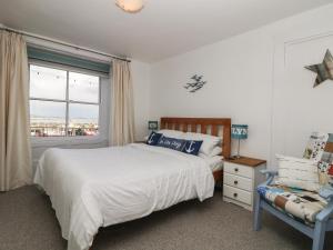 een slaapkamer met een bed, een raam en een stoel bij Westcliff in Penzance