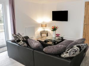 ein Wohnzimmer mit einem schwarzen Sofa und Kissen in der Unterkunft Willow Lodge in Cleeve Prior