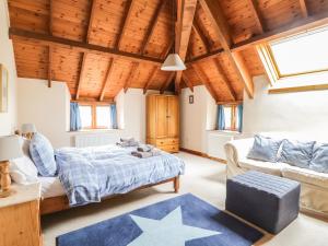 ein Schlafzimmer mit einem Bett und einem Sofa in der Unterkunft Swallows Cottage in Luppitt