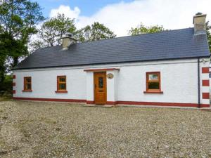 a small white house with a black roof at Ferrys in Portsalon