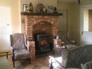 a living room with a brick fireplace with two chairs at Ferrys in Portsalon