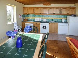 a kitchen with a table with a blue vase of flowers at Number 12 in Mulranny