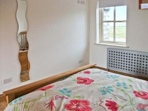 a bedroom with a bed with a floral comforter and a window at Cúnna Bán in Derreen