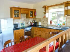 a kitchen with wooden cabinets and a table with a red at Ti Sheamuis in Clifden