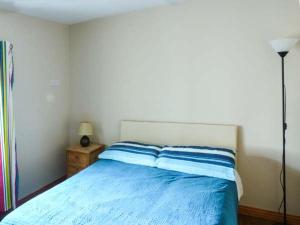 Schlafzimmer mit einem Bett mit blauer Bettwäsche und einer Lampe in der Unterkunft Ti Sheamuis in Clifden