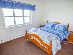 1 dormitorio con 1 cama con edredón azul y ventana en Sunset Beach Cottage, en Ballina