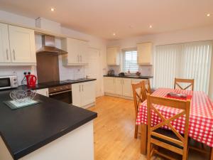 a kitchen with white cabinets and a table with a red table cloth at 63 Moinin in Kilkee