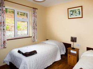 een slaapkamer met 2 bedden en een raam bij Rossbeigh Beach Cottage No 6 in Rossbeigh