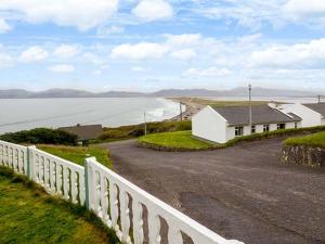 a white house on the side of a road next to the ocean at Rossbeigh Beach Cottage No 6 in Rossbeigh