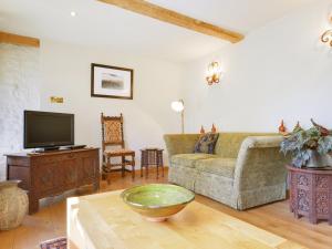 a living room with a couch and a tv at Pittards Farm Cottage in Lambrook