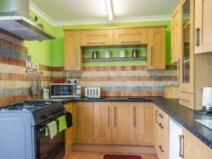 a kitchen with wooden cabinets and a stove top oven at Beach Bungalow in Rhyl