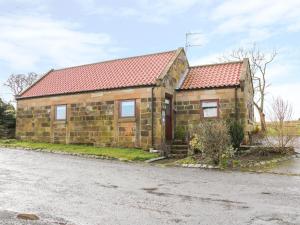 a stone house with a red roof on a street at Stable Cottage in Stoupe Brow