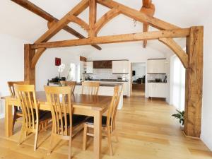 a kitchen and dining room with a wooden table and chairs at Bwthyn Clychau'r Gog in Clawdd-newydd