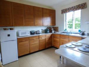 uma cozinha com armários de madeira e um frigorífico branco em Fiddlers Green em Bucknell