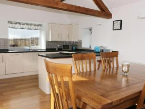 a kitchen and dining room with a wooden table and chairs at Bryn Eithin in Clawdd-newydd