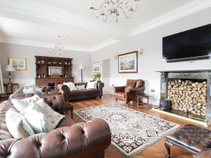 a living room with leather furniture and a fireplace at Bryn Derwen in Bangor