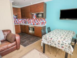 a kitchen with a table and a couch and a chair at Apartment 2 in Tenby