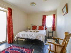 a bedroom with a bed with red curtains and a chair at Buttermere in Cockermouth