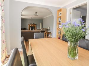 a dining room with a table with purple flowers in a vase at Ivy Cottage in Colchester