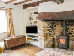 a living room with a stone fireplace and a television at Fern House in Craven Arms