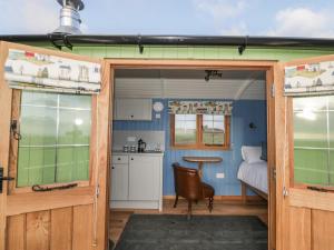 a kitchen with a door open to a tiny house at Cysgod y Bugail in Holyhead