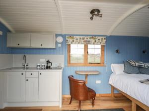 a bedroom with a bed and a table and a kitchen at Cysgod y Bugail in Holyhead