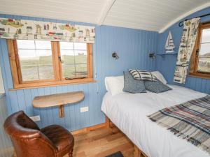 a bedroom with blue walls and a bed and a chair at Cysgod y Bugail in Holyhead