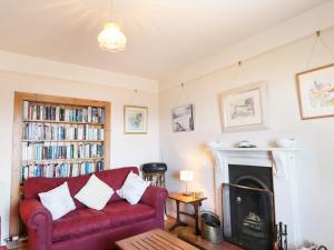 a living room with a red couch and a fireplace at St Magnus Haven in Pennan