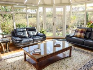 a living room with two leather couches and a coffee table at Castle Hill Farm in Hemyock