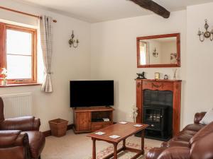 a living room with a tv and a couch and a table at Shire Cottage at Top Butterley Farm in Tansley