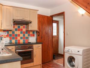 cocina con armarios de madera, lavadora y secadora en Shire Cottage at Top Butterley Farm, en Tansley