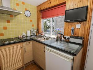 cocina con fregadero y TV en la pared en Maesawel Studio, en Harlech