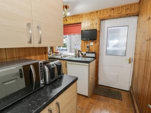 a kitchen with a sink and a microwave and a door at Maesawel Studio in Harlech