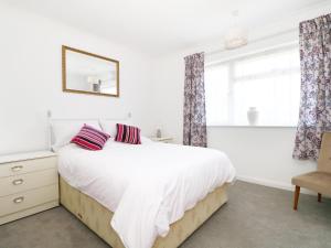 a white bedroom with a bed and a window at Sengador in Christchurch