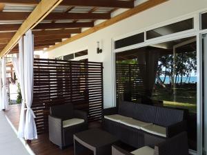 eine abgeschirmte Veranda mit einer Bank und Stühlen darauf in der Unterkunft Cahuita Inn in Cahuita