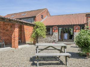 a wooden picnic table in front of a brick building at Sunset Cottage in Great Edston