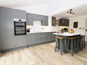 uma cozinha com armários cinzentos e um balcão branco em 21 Llwyn Gwalch Estate em Pwllheli