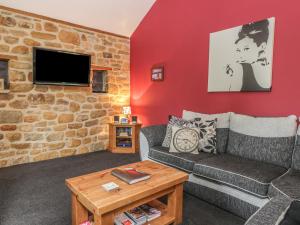 a living room with a couch and a brick wall at Little Byre Cottage in Sutton