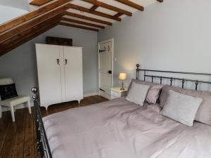a bedroom with a large bed and a wooden floor at Grafog Farm Cottage in Groeslon