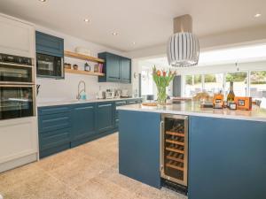 a kitchen with blue cabinets and a counter with wine racks at The Orchard in Crantock