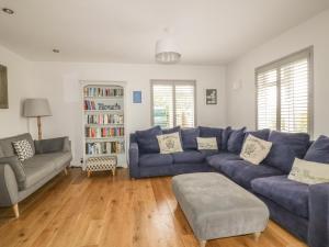 a living room with a blue couch and a book shelf at The Orchard in Crantock