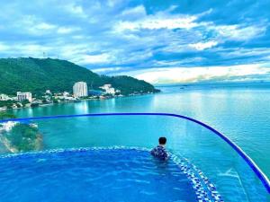 un hombre sentado en una piscina infinita con vistas al agua en Seaside Homestay Beachfront en Vung Tau