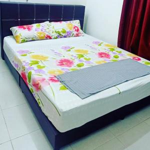 a bed with a floral bedspread and pillows on it at Homestay Musafir Apartment Seri Iskandar 2.0 in Seri Iskandar
