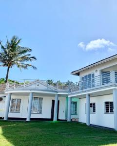 a large white house with a palm tree at Awesome Sea views! House near Zimbali in Densainagar