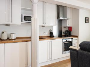 a white kitchen with white cabinets and a couch at 6 Mill Wharf in Berwick-Upon-Tweed