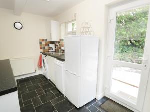 a kitchen with a white refrigerator and a window at Bwlch Yr Awel Cottage in Dolbenmaen