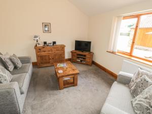 a living room with a couch and a tv and a table at Kitchen Cottage in Sutton